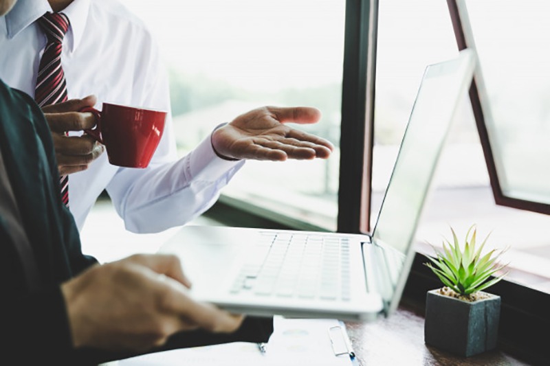 Homem bebendo café e mostrando sobre lean startup no notebook