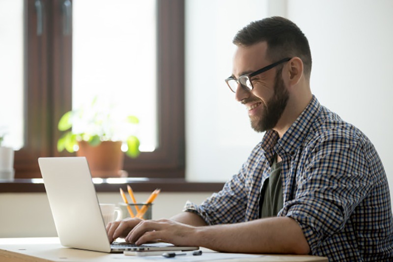 Homem feliz estudando em plataforma EAD pelo notebook